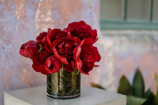 A Mother's Day flower arrangement featuring richly colored burgundy peonies, full and open.