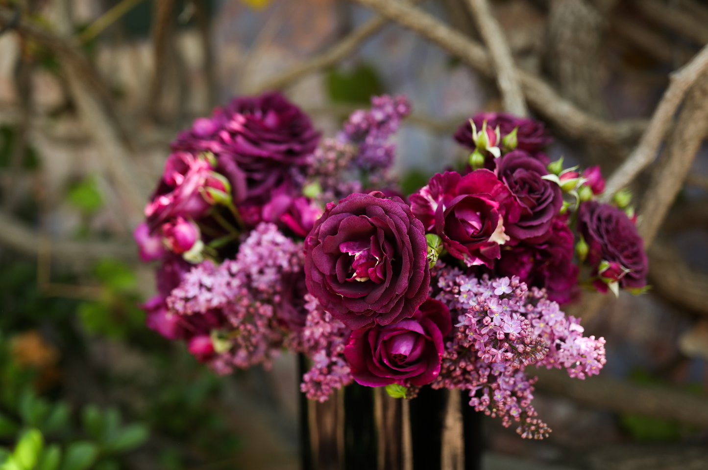 A close up of a flower arrangement to celebrate Mother's Day, featuring purple lilacs and Garden Roses from Rose Story Farm, in a black vase.